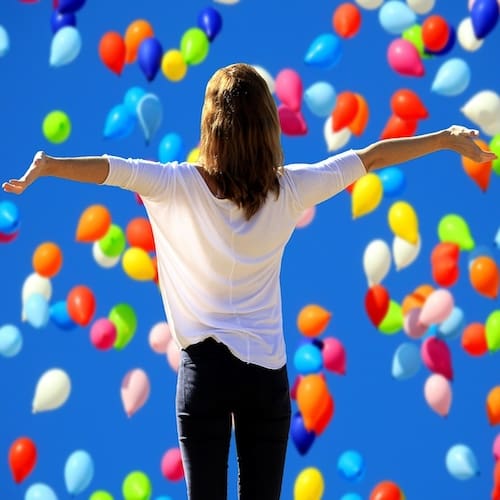 Confidence & Self Esteem Hypnotherapy for Confidence and Self Esteem - A confident woman in a shower of colourful balloons arms out wide